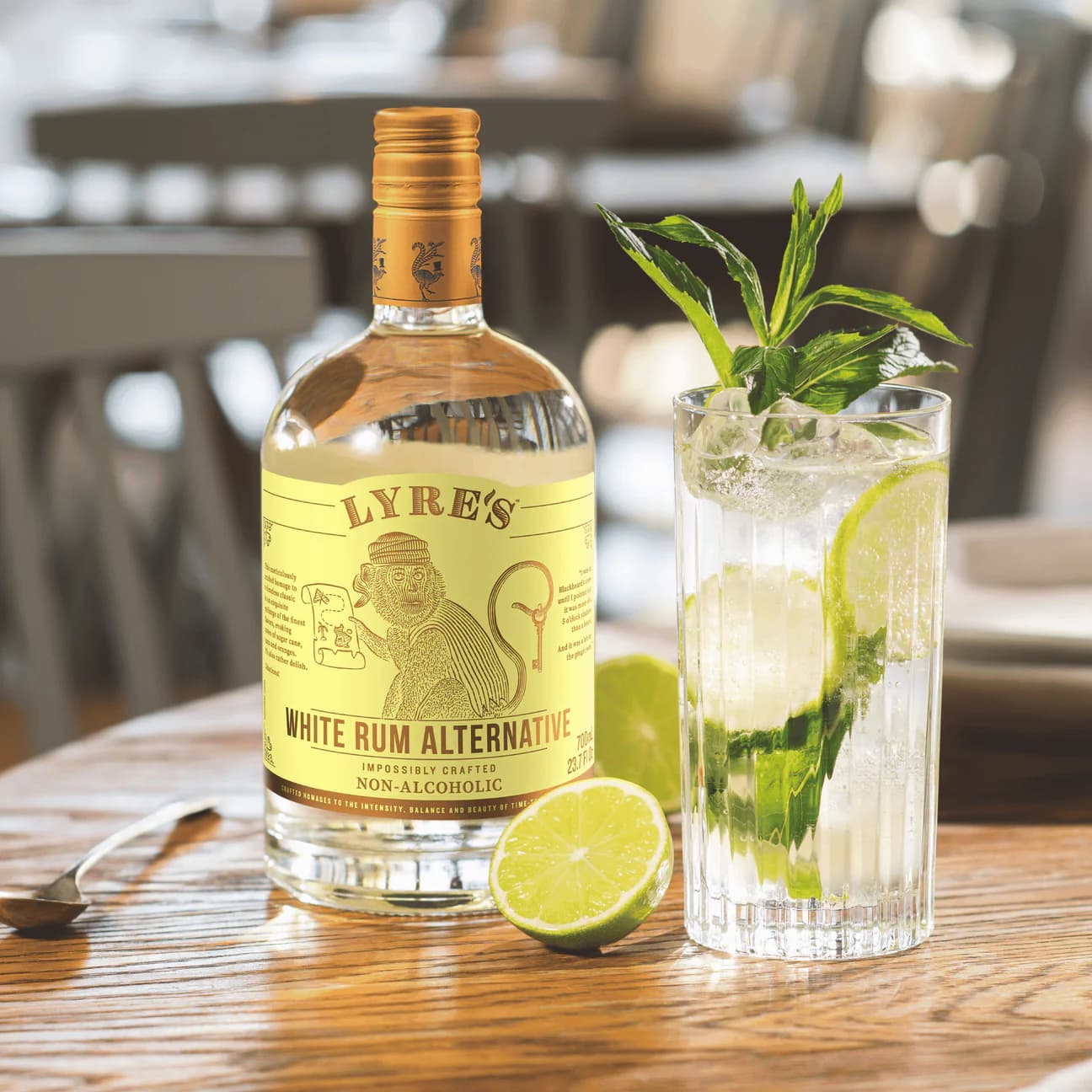 Lyre's White Rum Alternative bottle with a mojito cocktail on a wooden table.