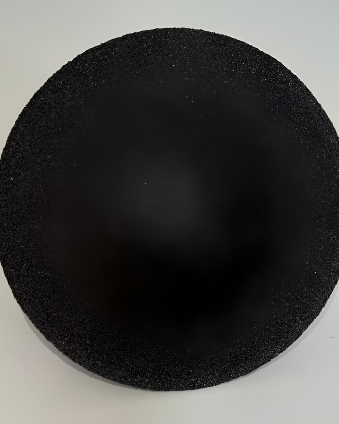 Black circular foam pad on a white background