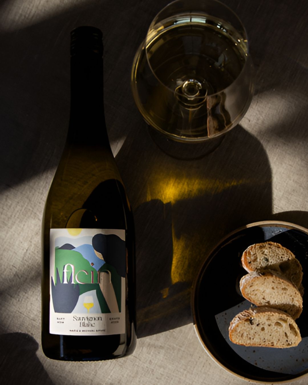 Flein Sauvignon Blanc grape juice bottle with a glass of juice and sliced bread on a table