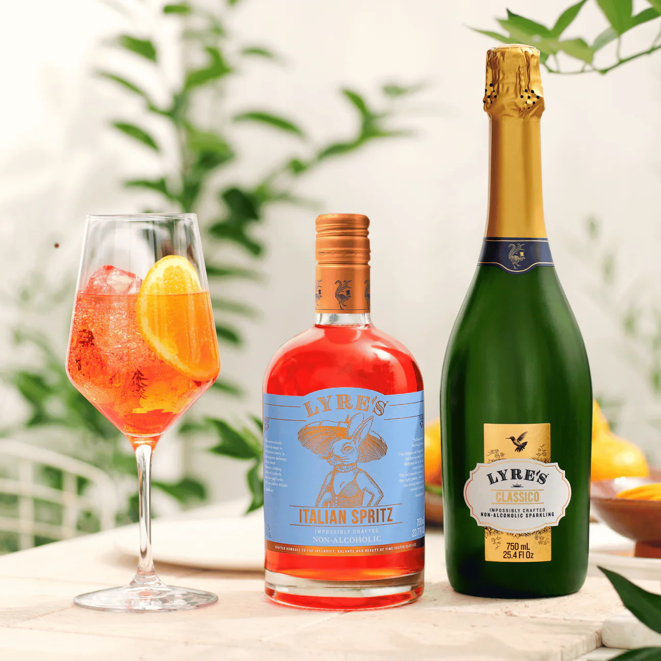 Bottle of Lyre's Italian Spritz and bottle of prosecco with a glass of spritz on a table.