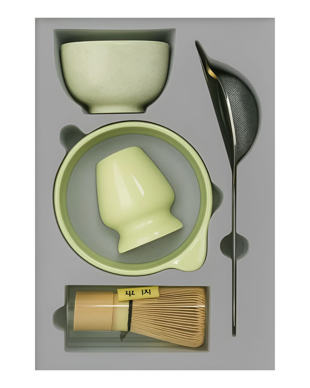 Tea-making set with green ceramic items and bamboo whisk on a gray background