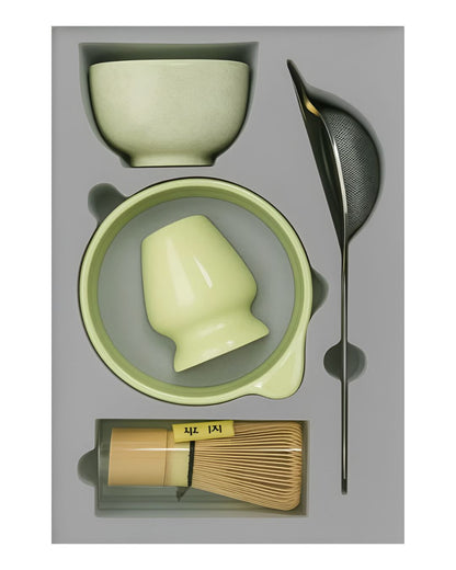 Tea-making set with green ceramic items and bamboo whisk on a gray background